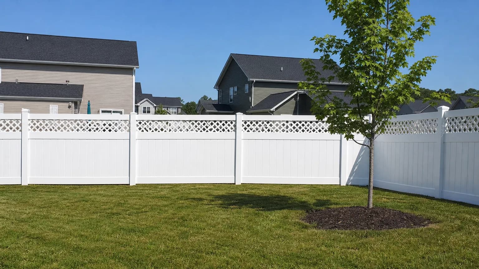 White vinyl privacy fence with a lattice top in a new-subdivision backyard
